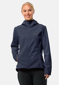 Jachetă softshell bleumarin cu un design ajustat, fermoar complet, glugă și buzunare laterale. Logo pe piept, textură netedă și material elastic.
