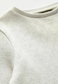 Ljusgrå sweatshirt med en strukturerad stickad mönstring, med rundad halsringning och subtila diamantmotiv. Mjuk, andningsbar material med en slät yta.