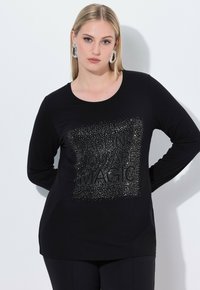 Schwarzes Langarmshirt mit einer strukturierten, metallisch-silbernen Grafik, die in einem quadratischen Muster "DARLING YOU ARE MAGIC" zeigt. Weicher Stoff.