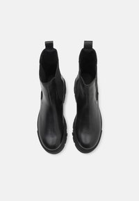 Botines de cuero negro hasta el tobillo con paneles laterales elásticos, acabado suave, puntera redonda y suela de goma texturizada para mayor tracción.
