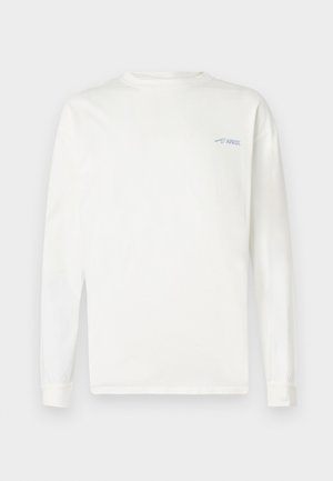 Camiseta blanca de manga larga con cuello redondo y pequeño logo azul "ARKK" en el pecho izquierdo, mostrada sobre un fondo claro y liso.