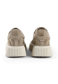 Sneaker beige in suede con una suola spessa e rigata. La tomaia testurizzata presenta perforazioni, una linguetta e un design senza cuciture che accentua il comfort.