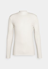 Camiseta de manga larga, cuello alto y acanalada en color crema. Textura suave con una silueta ajustada y sin logotipos ni patrones visibles.