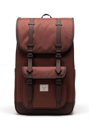 Zaino in tessuto marrone con spallacci e fibbie in pelle scura, tasca frontale e etichetta del marchio Herschel su sfondo bianco.