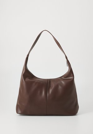 Sac à bandoulière en cuir marron avec une seule sangle et une couture verticale centrale, posé sur un fond clair uni.
