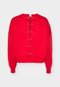 Sudadera roja corta con mangas largas, con escote redondo y diseño de espalda con cordones y ojales plateados. Textura suave.