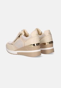 Zapatillas beige con paneles de malla, detalles dorados y suela en cuña. Cuenta con un zipper lateral y suela en contraste blanca y marrón.