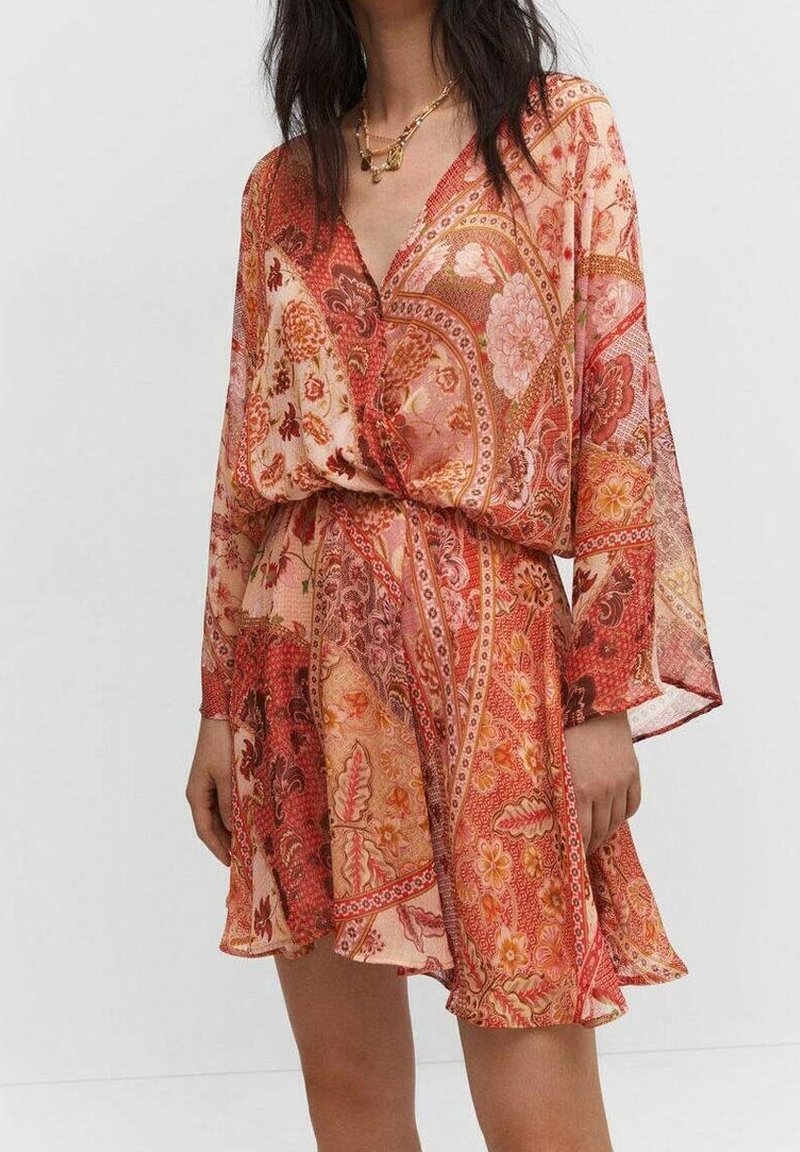 Robe à motif floral dans des tons de rouge et pêche, fabriquée en tissu léger. Elle présente un col en V et des manches longues amples, avec une taille ceinturée.