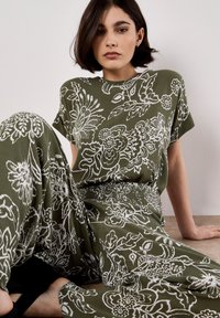 Conjunto de patrón floral verde, confeccionado con tela suave; presenta mangas cortas, un corte relajado y una cintura elástica para los pantalones.