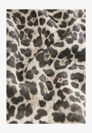 Tkanina w wzór lamparta z beżowym tłem i nieregularnymi czarnymi plamami, prezentująca miękką, teksturowaną powierzchnię.