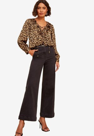 Leopard print blouse with ruffled neckline and ties, paired with high-waisted black wide-leg pants and strappy black heels.