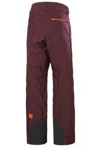 Bordeaux sneeuwbroek met een zwarte onderrand. Beschikt over een oranje ritszak en een logo-patch. Gemaakt van een gladde, duurzame stof.