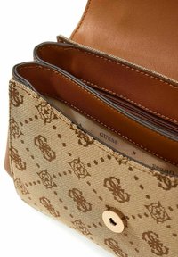 Sac à main en tissu marron à motifs avec un intérieur en cuir lisse, comprenant deux compartiments et une fermeture à bouton-pression. Accents en métal doré.