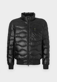 Giubbotto puffer nero con finitura lucida, caratterizzato da un colletto alto, chiusura con zip e imbottitura orizzontale. Include una tasca sul petto e polsini a costine.