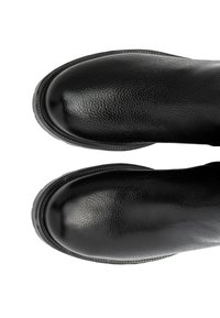 Czarne skórzane buty z teksturowanym wykończeniem, zaokrąglonym czubkiem, przeszyciami wzdłuż podeszwy oraz niskim, lekko podwyższonym obcasem.