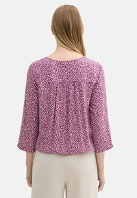 Lila gemusterte Bluse mit Dreiviertelärmeln, Raffung im Rücken, fließendem Design und Rundhalsausschnitt.