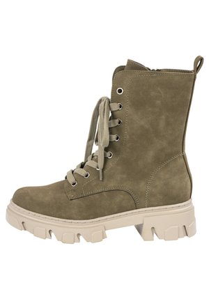 Bottines en suède olive avec semelle en caoutchouc beige épaisse, bout rond et œillets en métal. Comprend un laçage à l'avant et une languette à l'arrière.