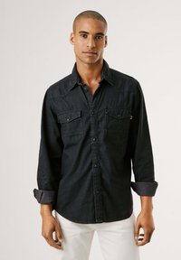 Dunkelblaus Denim-Hemd mit langen Ärmeln, zwei Brusttaschen, Druckkn�öpfen und kontrastierendem Stoff an den umgeschlagenen Manschetten. Verfügt über einen klassischen Kragen.
