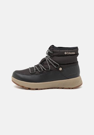 Zwarte Columbia waterdichte winterlaars met beige zool en grijze gebreide veters, enkellaarshoog gewatteerde kraag en gestructureerde profielzool.