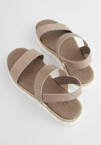 Bruna mockaklackar med elastiska remmar, en strukturerad sula och en vit espadrillastil. Utformade för komfort och enkel användning.