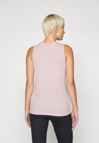 Light pink sleeveless top with a soft texture and rounded neckline, featuring a clean design and a loose fit, paired with black leggings.