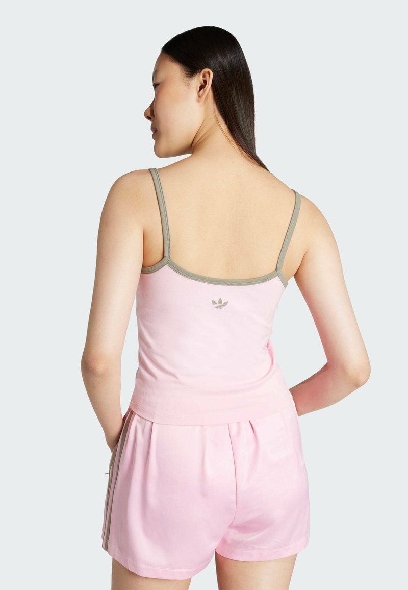 Helles rosa Tanktop mit dunkelgrünem Saum und kleinem Logo auf der Rückseite, kombiniert mit passenden rosa Shorts mit Seitenstreifen und einem lässigen Schnitt.