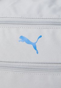 Grijze stoffen tas met een blauw Puma-logo, voorzien van een rits en een gestructureerd oppervlak. Compact ontwerp, geschikt voor accessoires.