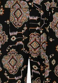 Crna tkanina s složenim geometrijskim uzorcima u ružičastoj, narančastoj i krem boji. Uključuje naglaske u obliku strelica i cvjetnih motiva.