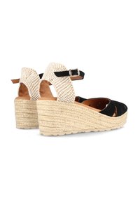 Sandalias de cuña de ante negro con una correa de tobillo trenzada beige y hebilla, que presentan diseños recortados y una plataforma de yute texturizado.