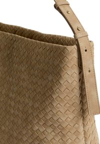 Borsa tote in pelle beige intrecciata con una texture liscia, dotata di un ampio apertura in alto e di una tracolla regolabile con dettagli in hardware dorato.