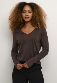 Braunes Langarmshirt mit V-Ausschnitt, aus weichem Material gefertigt, mit engen Ärmeln und einer lockeren Silhouette.