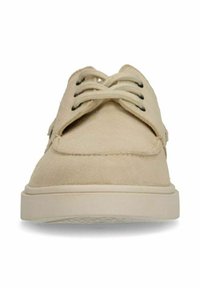 Beige suède schoenen met een ronde neus, voorzien van zwarte veters en een textuursgewijze witte zool. Stikseldetails zijn zichtbaar op het bovenwerk.