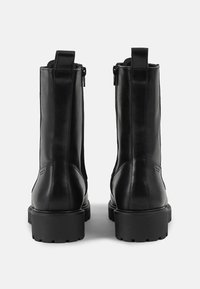 Schwarze Leder-Ankle-Boots mit glatter Oberfläche, flachen Gummisohlen, seitlichen Reißverschlüssen und Zuglaschen an der Rückseite für ein einfaches Anziehen.