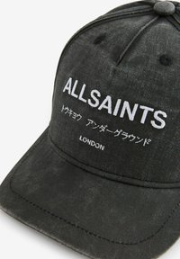 Must värviline denimmüts, millel on tõmblukuga valge tekst "ALLSAINTS" ja lisakirjad, ümmarguse krooniga ja kumerate äärega.