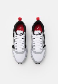 Black and grey athletic shoes with white mesh upper, lace closure, and red accents on the heel and inner lining. Logo on the tongue and side.
