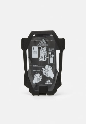 Support de téléphone mobile noir avec un devant transparent affichant des instructions. Il présente un design durable et une fonctionnalité ambidextre pour divers objets.
