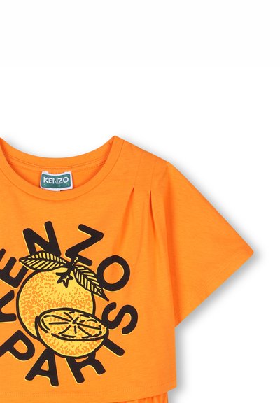 T-shirt orange à manches courtes avec un col rond. Présente un motif noir d'une orange et le texte "KENZO PARIS". Coupe légèrement décontractée.