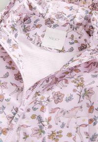 Light pink jacket with unicorn and floral patterns, white zipper, and a "NEXT" brand label inside the collar.