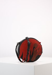 Borsa rotonda in suede rosso con dettagli in pelle nera e un design fiamma prominente. Tracolla regolabile con hardware in argento.