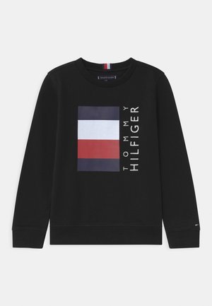 Czarna bluza z crewneckiem z logo flagi Tommy Hilfiger w kolorach granatowym, białym i czerwonym oraz pionowym napisem "Tommy Hilfiger" obok logo.