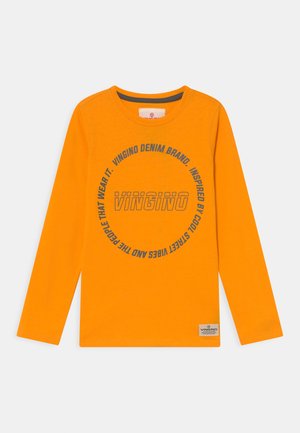 Maglietta arancione brillante a maniche lunghe con scollatura rotonda, testo circolare blu navy e logo "VINGINO" al centro, etichetta piccola all'orlo inferiore.