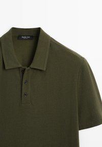 Polo à manches courtes vert olive avec col et trois boutons noirs, étiquette "Massimo Dutti" à l'intérieur du col.