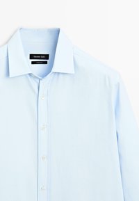 Camicia button-up azzurra con colletto classico, maniche lunghe e una texture liscia. Etichetta con logo all'interno del colletto.