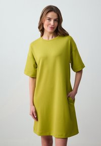 Abito t-shirt in cotone verde lime con maniche corte, scollatura rotonda e tasche laterali. Tessuto morbido e vestibilità comoda.