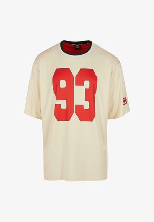 T-shirt crème à manches courtes avec un grand graphique rouge "93" sur le devant et un détail de col noir et rouge. Texture de tissu douce.