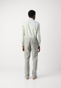 Light green long-sleeve shirt with a button-down collar, paired with gray textured trousers featuring an elastic waistband and two back pockets.