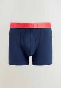 Sötétkék boxernadrág puha anyagból, élénk rózsaszín gumírozott derékkal, amelyen a "NEXT" felirat található, és szoros illeszkedésű kialakítással.