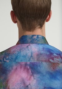 Košile s krátkým rukávem a límečkem v mnohobarevném vzoru ve stylu akvarelu, obsahující odstíny modré, fialové a růžové s hladkou texturou.