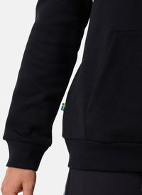 Sweatshirt noir avec une texture douce, doté d'une poche kangourou et de poignets côtelés. Petite accentuation du drapeau suédois près de l'ourlet.