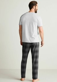 Gray cotton T-shirt and black plaid pajama pants. The fabric is smooth, with short sleeves and a relaxed fit. The pants feature a checkered pattern.